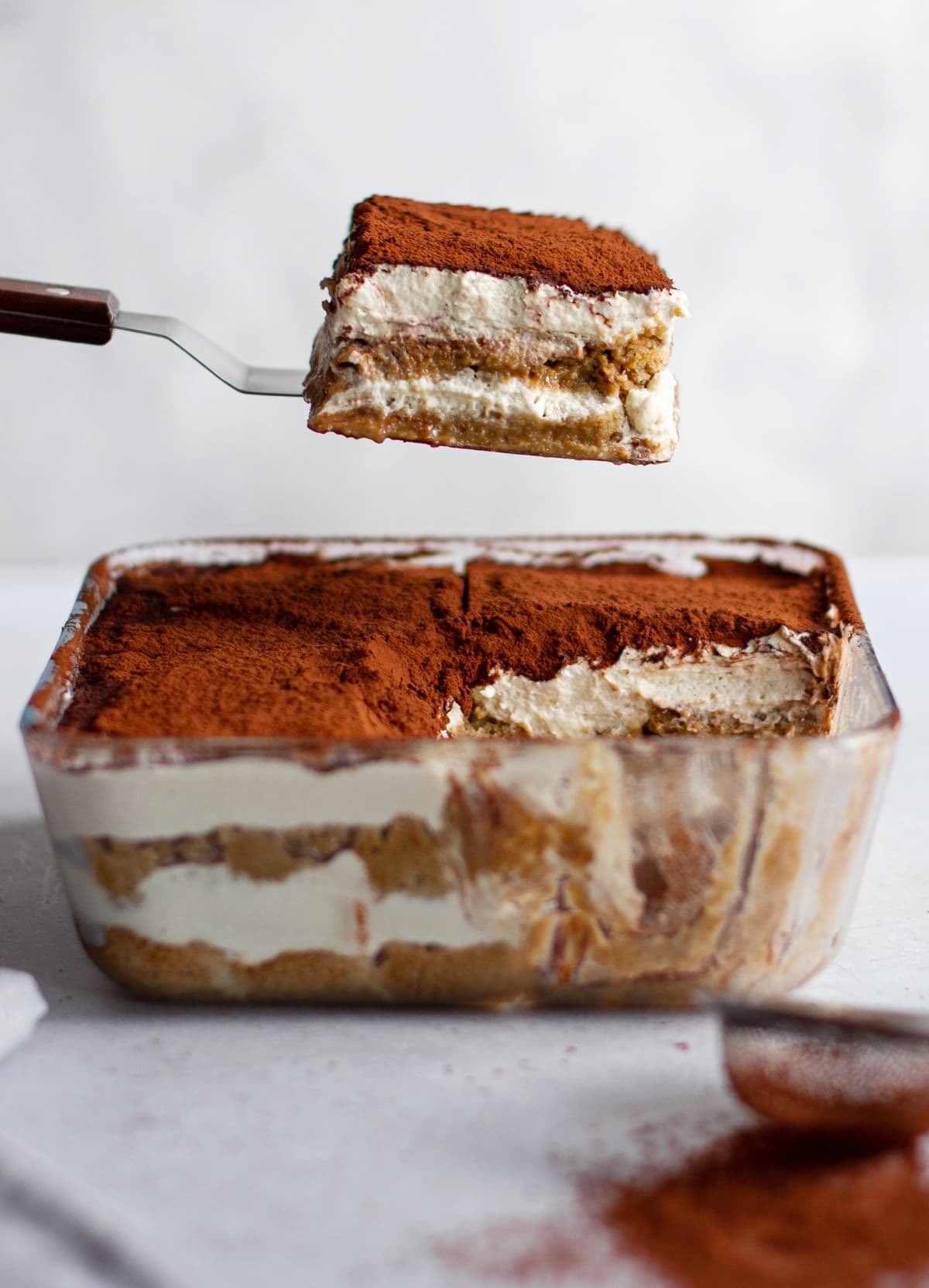 presenting-one-piece-of-vegan-tiramisu-over-glass-pan
