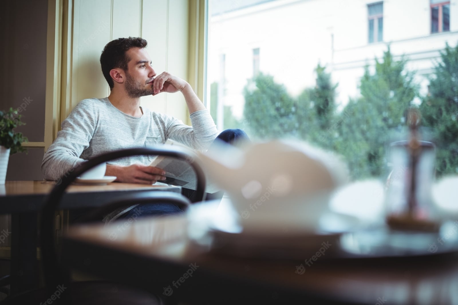 hombre-reflexivo-mirando-ventana-mientras-que-lectura-periodicos_1170-544