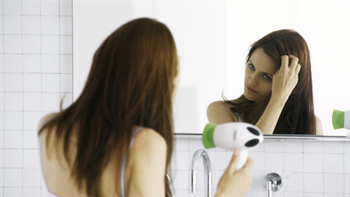 una-mujer-alisandose-el-pelo-con-un-secador