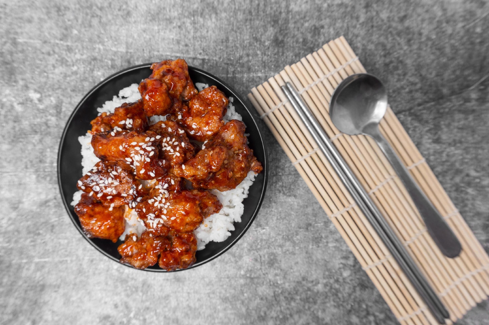 top-view-rice-topped-korean-spicy-deep-fried-chicken-topped-white-sesame-on-the-gray-concrete-table-popular-street-food-in-korea-free-photo
