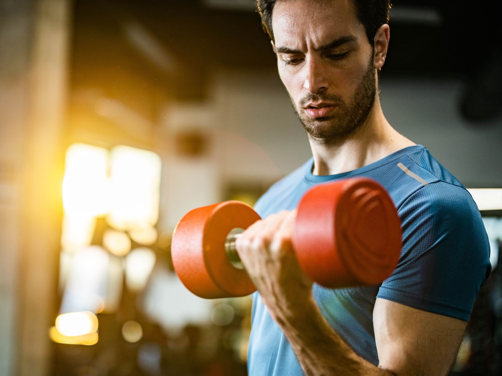 sportsman-exercising-with-dumbbell-in-a-gym-royalty-free-image-1725950419