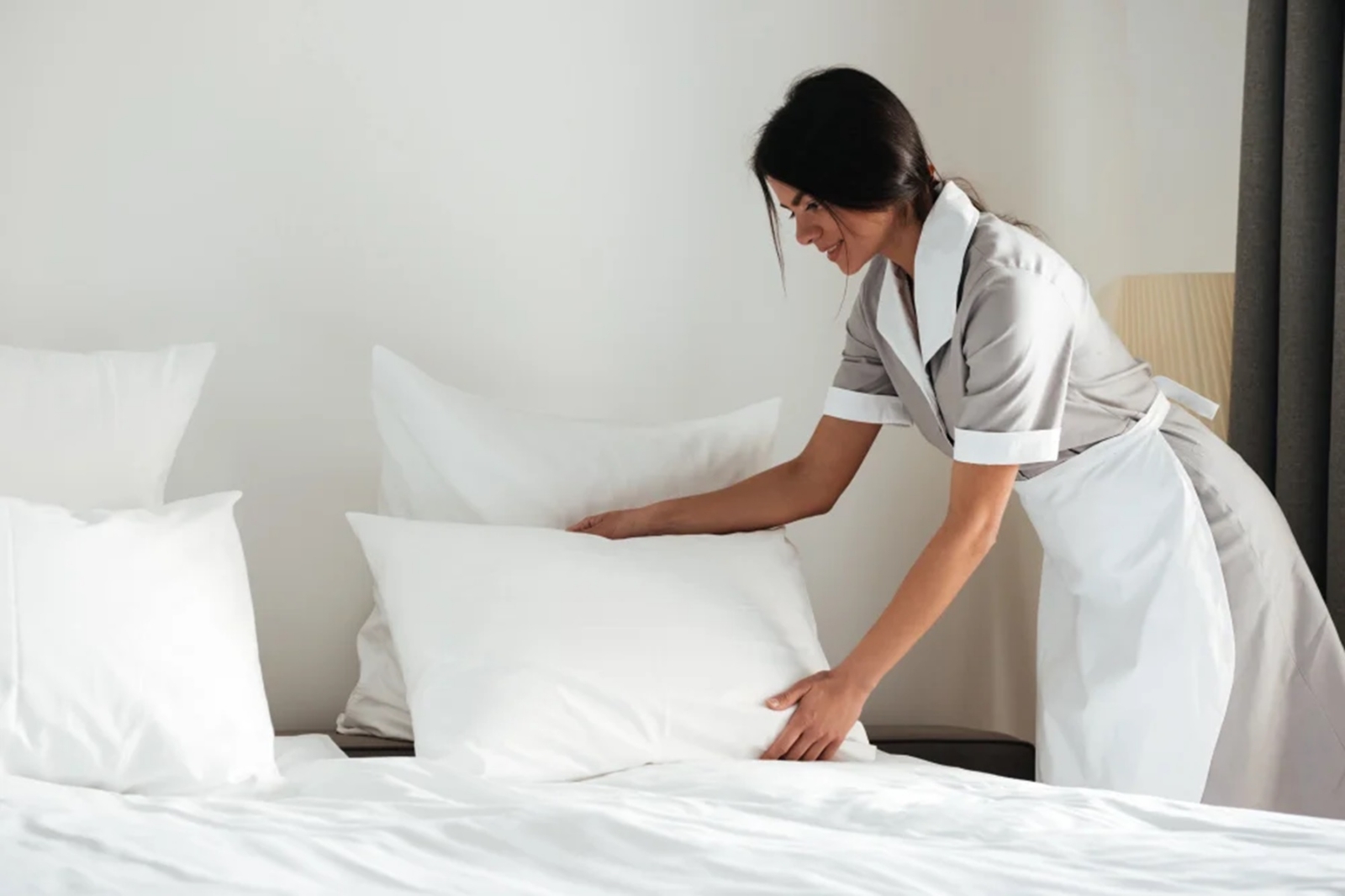 young-hotel-maid-setting-up-pillow-on-bed-1-1